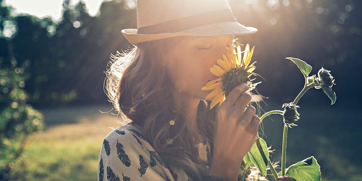 Girl smells sunflower in the sun - vitamin D